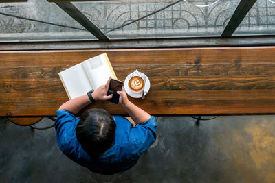 High angle view of man reading book on table