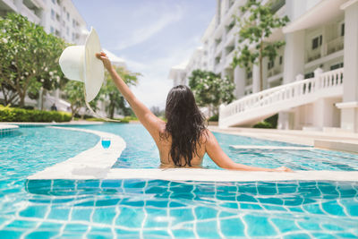 Rear view of woman walking in swimming pool