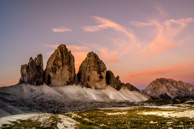 Rock formations by sea against sky during sunset