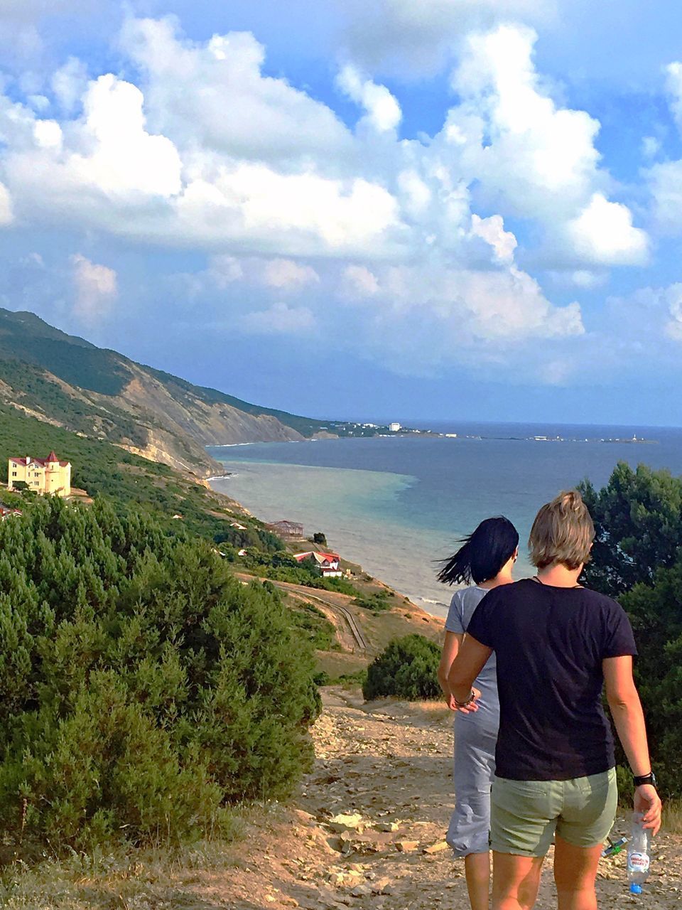 REAR VIEW OF MAN AND WOMAN LOOKING AT VIEW OF SEA