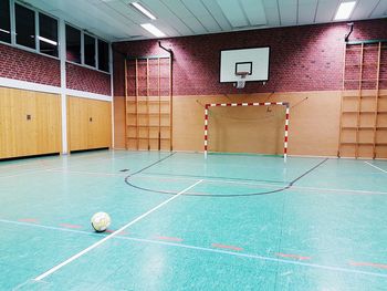 View of empty gym with soccer ball and goal and basketball hoop