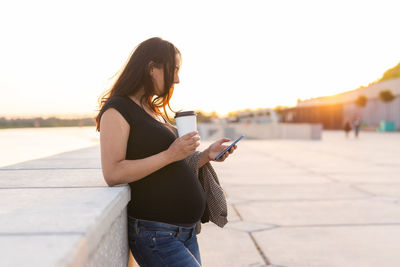 Woman standing on mobile phone against sky