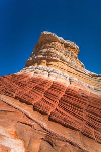 Low angle view of rock formations against clear blue sky at white pocket