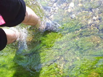 Midsection of man holding water flowing in river