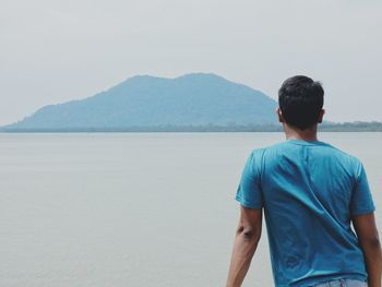 Rear view of man standing in front of sea