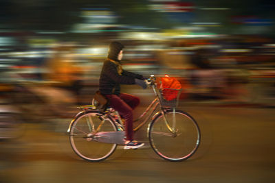 Rear view of man riding bicycle on street