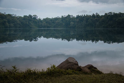 Scenic view of lake by trees against sky