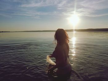 Woman splashing water in sea against sky