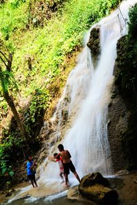Male friends enjoying waterfall in forest