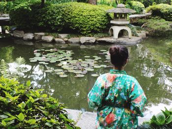 Rear view of woman against pond