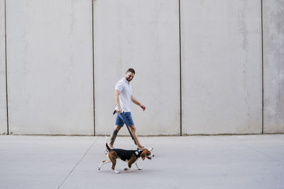 Full length of woman with dog against wall
