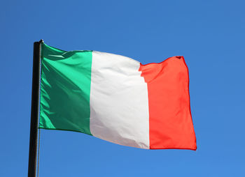 Big italian flag waving in blue sky with vivid red and white green colors