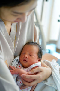 Close-up of cute baby girl lying on bed at home