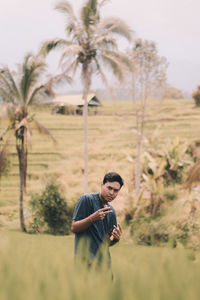 Young man standing on palm tree on field