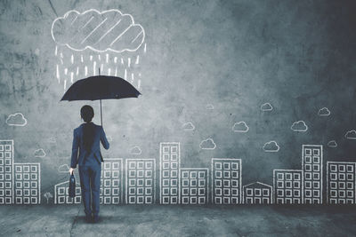 Rear view of man with umbrella standing in rain