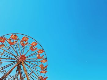 Low angle view of ferris wheel against clear blue sky