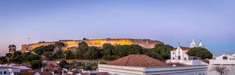 Panoramic view of trees and buildings against clear sky