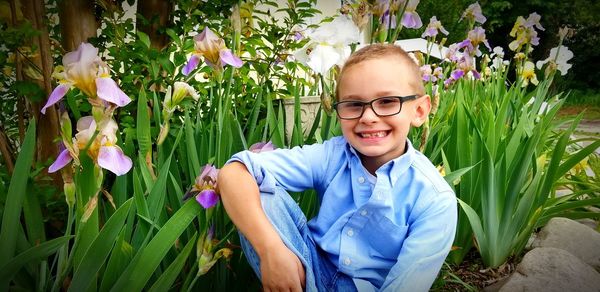 Portrait of smiling girl standing by flowering plants