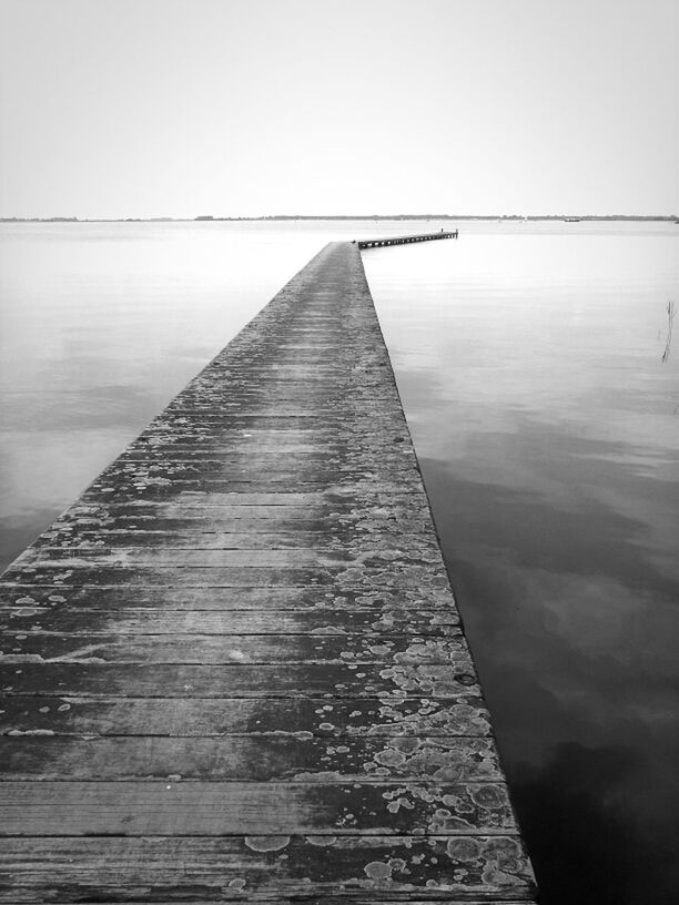 built structure, architecture, sky, connection, clear sky, the way forward, diminishing perspective, low angle view, water, bridge - man made structure, day, outdoors, no people, engineering, pier, transportation, copy space, building exterior, railing, bridge