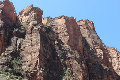 Low angle view of rocky mountains against clear sky