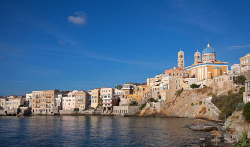 Buildings by sea against sky