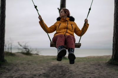 Full length of woman sitting on swing at playground