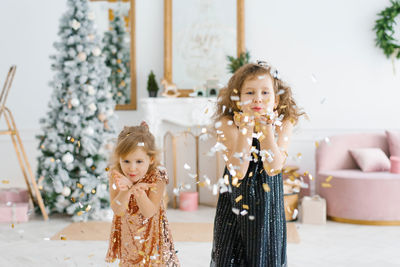 Two happy kids celebrating new year and christmas eve at home. they turn into confetti
