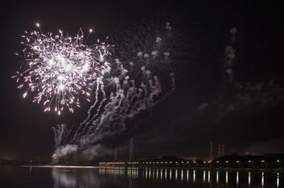 Firework display over river against sky at night