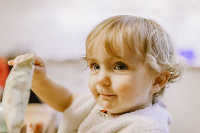 Close-up of cute baby girl holding packet