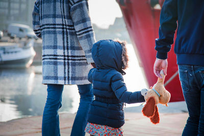 Girl with parents walking by river