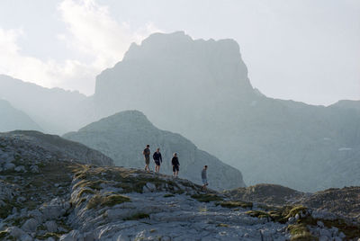 Low angle view of male friends walking on mountain against sky
