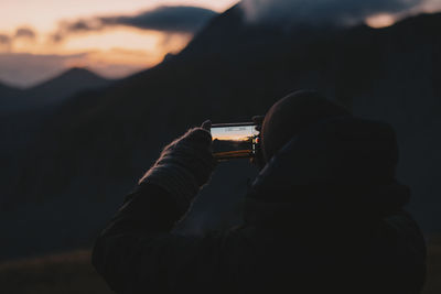 Midsection of man photographing at sunset