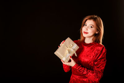 Portrait of a smiling young woman against black background