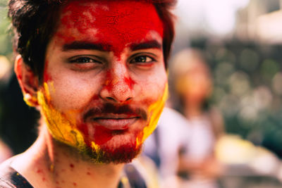 Close-up portrait of young man with powder paint on face during holi