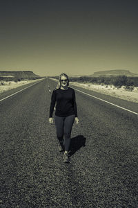 Portrait of young woman standing on road against sky