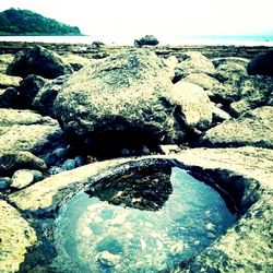 Close-up of rocks in sea against sky