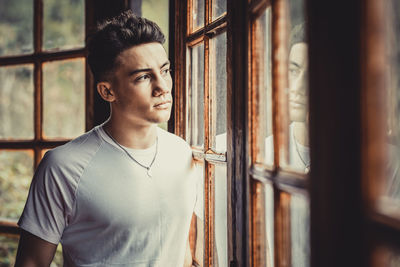 Portrait of young man looking through window