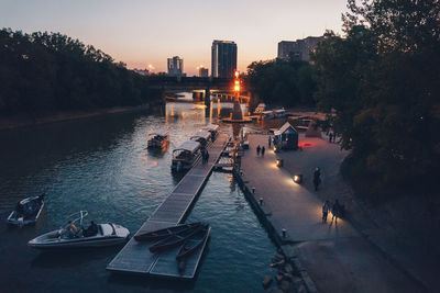 People on sidewalk in city against sky at sunset