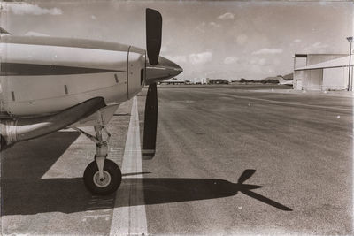 Airplane on airport runway against sky