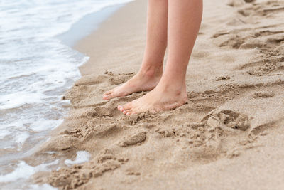 Low section of woman standing at beach