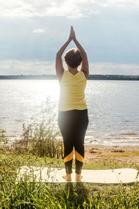 Rear view of woman standing by sea against sky