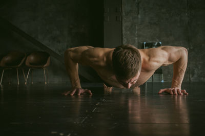 Shirtless young man doing push-ups in gym