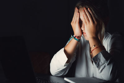 Side view of young woman using laptop at home