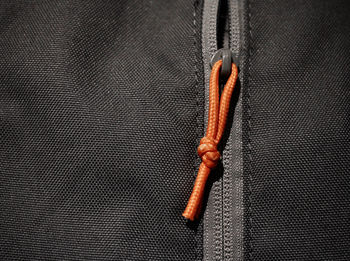 Close-up of orange zipper  over grey background