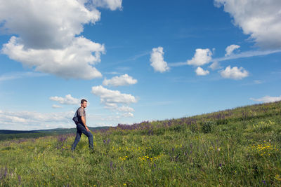 Adult man hiking on wooded hills in summer