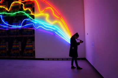 Full length of woman photographing against multi colored light art in maxxi national museum