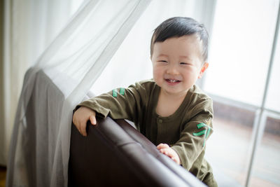 Portrait of boy looking through window at home