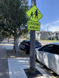 Road sign by street in city against sky