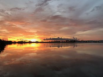 Scenic view of lake against dramatic sky during sunset