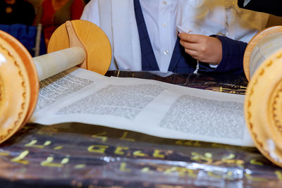 Midsection of person sitting by religious book on table